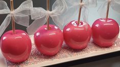 four candy apples are lined up on a tray