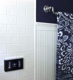 a bathroom with a blue and white shower curtain next to a toilet paper dispenser