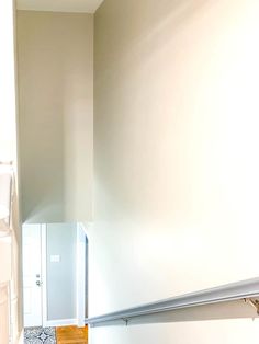 an empty bathroom with white walls and wood flooring on the wall, along with toilet paper dispenser