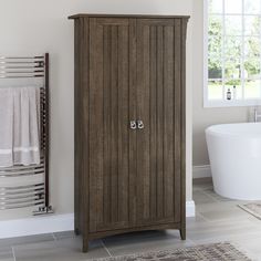 a bathroom with a large wooden cabinet next to a bathtub and towel dispenser