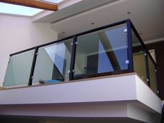 a balcony with glass railings and skylight above the stairs in a modern home