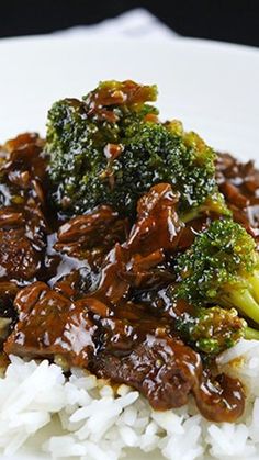 a white plate topped with rice and broccoli covered in sauce on top of it