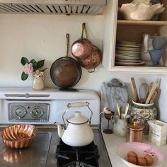 a stove top oven sitting inside of a kitchen next to pots and pans on the wall