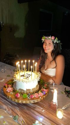 a woman sitting in front of a cake with lit candles