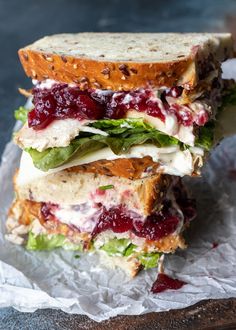 two sandwiches stacked on top of each other with cranberry sauce and lettuce