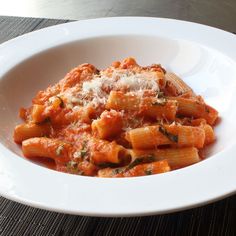 a white bowl filled with pasta covered in sauce and parmesan cheese on top