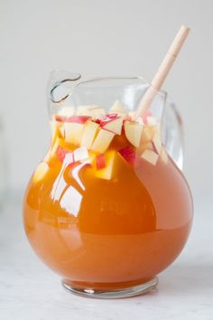 a pitcher filled with orange liquid and sliced apples