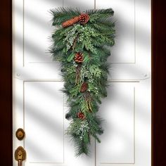 a cross decorated with pine cones and evergreens hangs on the front door to give it a festive feel