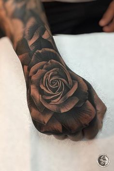 a black and white rose tattoo on the left hand