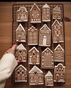 a person is decorating gingerbread houses with icing on a wire cooling rack