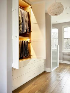 an open closet with clothes hanging on the wall and wooden flooring in front of it