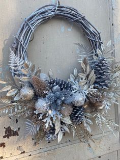 a wreath with pine cones and silver leaves