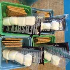 four plastic containers filled with crackers and marshmallows on top of a table