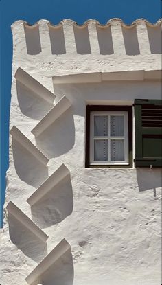 a white building with green shutters and a window