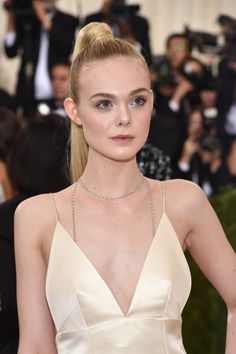 a woman with blonde hair wearing a halter top and diamond necklace on the red carpet