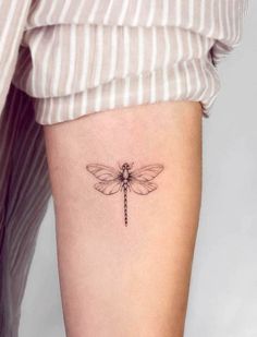 a small dragonfly tattoo on the right side of the leg, it is black and white