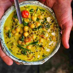 two hands holding a bowl filled with soup