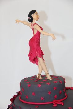 a woman in a red dress is standing on top of a gray and red cake