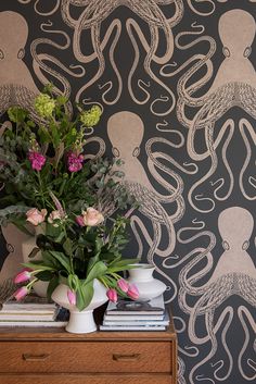 a vase filled with flowers sitting on top of a wooden dresser next to a wall