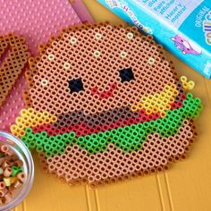 there is a plastic bead hamburger on the table next to a bowl of cereal