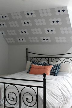 a bed with white sheets and pillows in a room that has a painted flower design on the wall