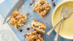 several pieces of dessert sitting on top of a blue cutting board next to a yellow plate