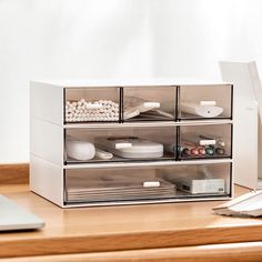 a laptop computer sitting on top of a wooden desk next to a stack of drawers