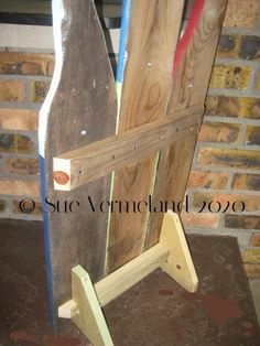 a wooden chair made out of old boards and woodworking tools in front of a brick wall