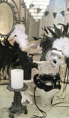 black and white masks are on display in front of a chandelier with candles