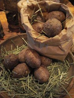 a wooden bowl filled with potatoes sitting on top of a table next to a pile of hay