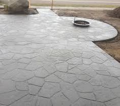 an outdoor patio with large rocks on the ground and a fire pit in the middle