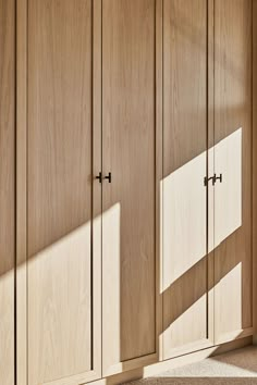 an empty room with wooden cupboards and sunlight coming through the window onto the floor