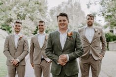 a group of men standing next to each other wearing suits and ties with flowers on their lapels