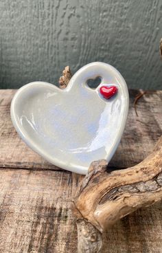 a heart shaped dish sitting on top of a piece of drift wood next to a branch