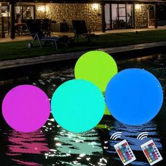 three balls floating on top of water in front of a house at night with wifi