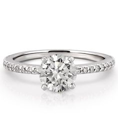 a white gold engagement ring with diamonds on the band and a round cut diamond in the center