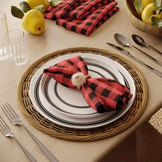 a place setting with plaid napkins, silverware and lemons on the table