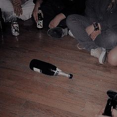 a group of people sitting on the floor next to each other with bottles in front of them