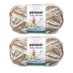 two balls of bernat baby blanketing yarn in white and beige, on top of each other