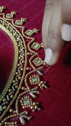 a woman is working on a gold tiara with beads and stones in the shape of a heart