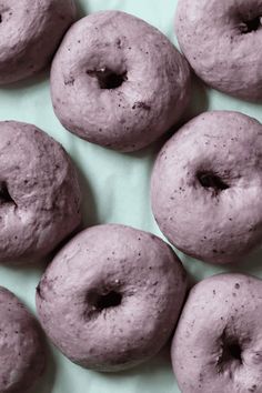 six doughnuts that have been glazed in purple glaze on a green surface