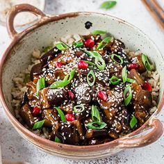 a bowl filled with rice and vegetables on top of a white table next to chopsticks