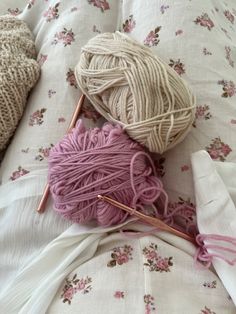 two skeins of yarn sitting on top of a bed next to a pillow