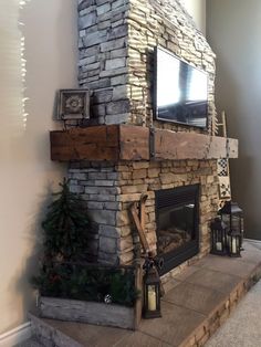 a stone fireplace with a flat screen tv mounted above it and christmas decorations on the mantle