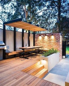 an outdoor dining area is lit up by lights on the outside wall and wooden flooring