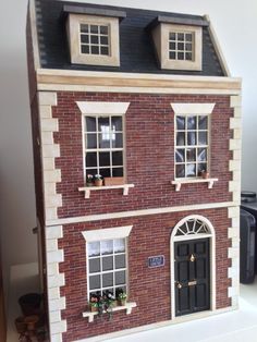 a doll house made out of red bricks with windows and shutters on the second floor