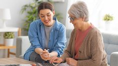 two women sitting at a table with a calculator in front of their laptop