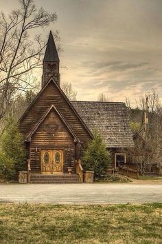 an old wooden church with a steeple on the front and stairs leading up to it