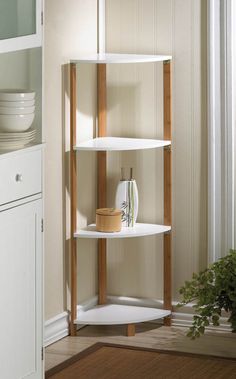 a corner shelf in the corner of a room with plates and bowls on it, next to a potted plant