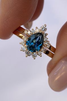 a woman's hand holding an engagement ring with a blue diamond